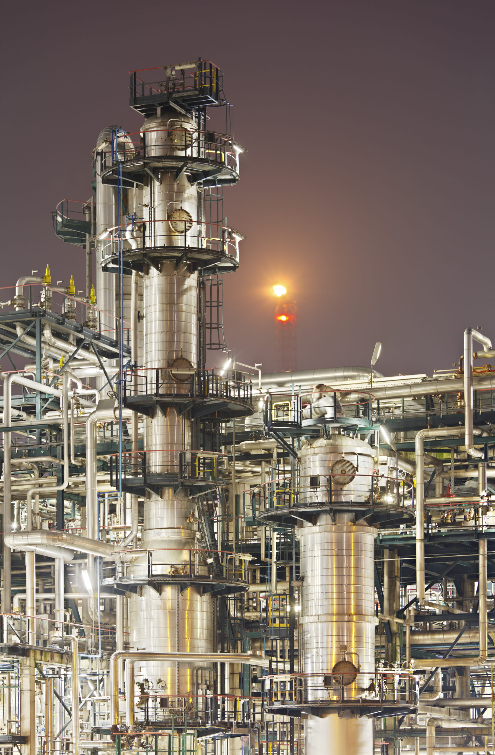 An oil refinery detail shot with a flare in the background.